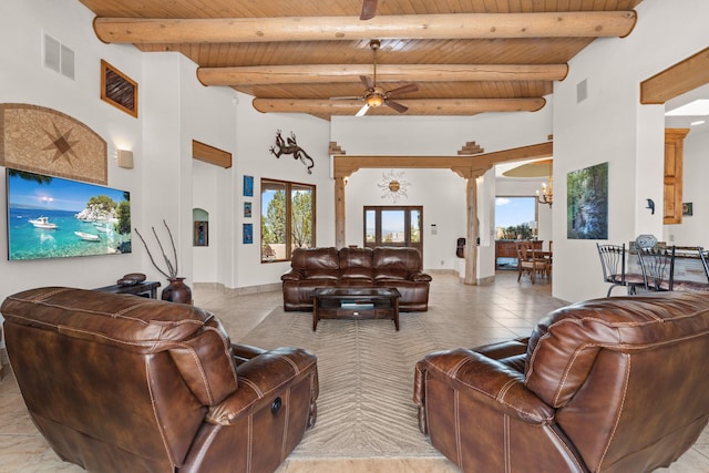 living area featuring ceiling fan with notable chandelier, wooden ceiling, visible vents, and a high ceiling