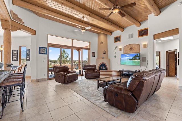living area featuring a towering ceiling, visible vents, ceiling fan, wood ceiling, and light tile patterned floors