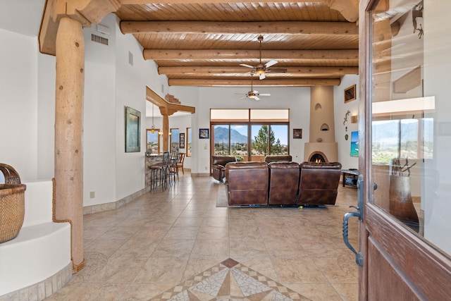 living area with light tile patterned floors, visible vents, wooden ceiling, ceiling fan, and beamed ceiling