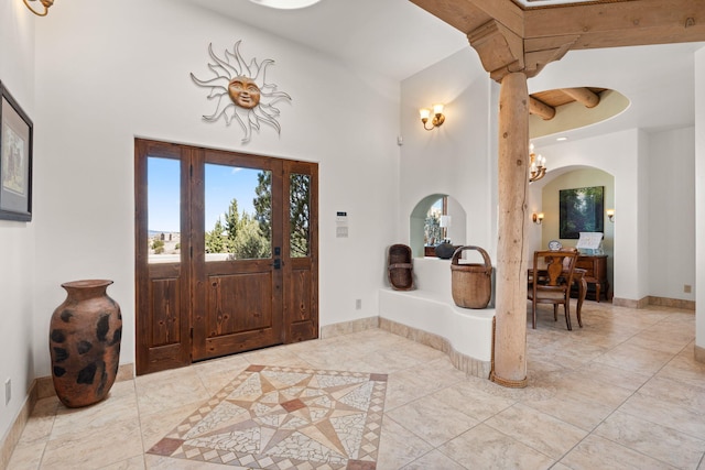 entrance foyer with light tile patterned floors, arched walkways, a high ceiling, and baseboards