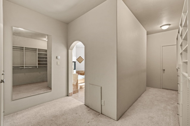 hallway featuring arched walkways and carpet