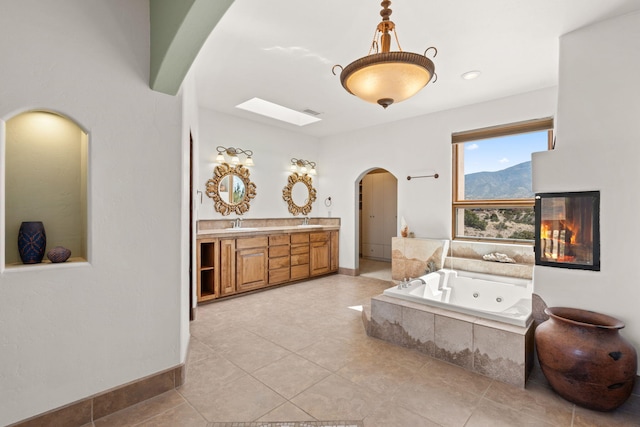bedroom featuring a sink, a skylight, light tile patterned flooring, arched walkways, and visible vents