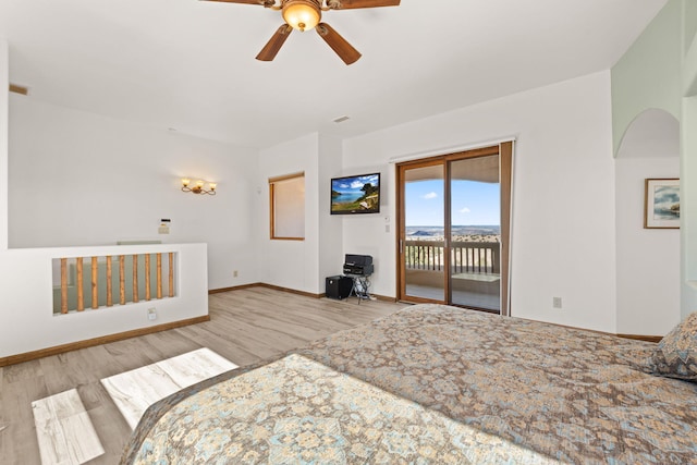 bedroom featuring arched walkways, wood finished floors, access to exterior, and baseboards