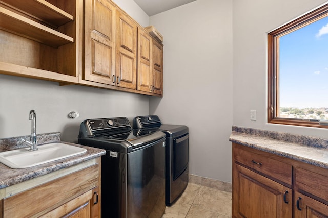 washroom with washer and dryer, cabinet space, and a sink