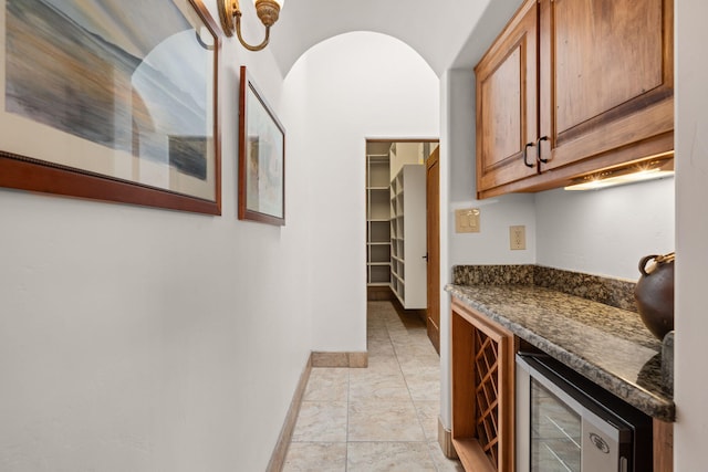interior space featuring dark countertops, brown cabinetry, baseboards, and wine cooler