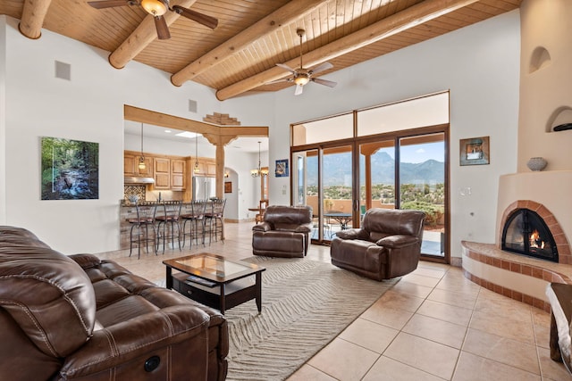 living area with wood ceiling, light tile patterned floors, ceiling fan, and a mountain view