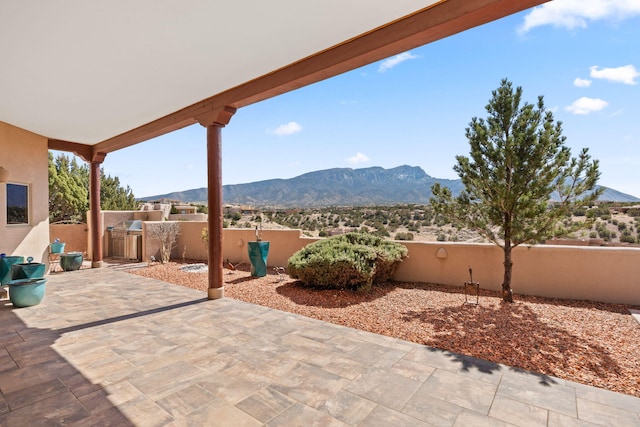 view of patio / terrace with fence, an outdoor kitchen, and a mountain view