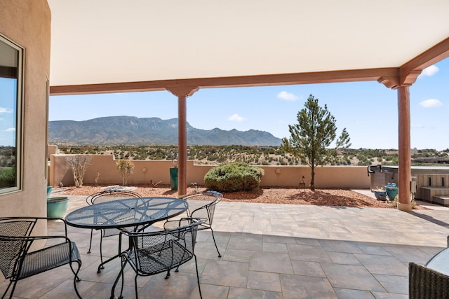 view of patio with fence, outdoor dining area, and a mountain view