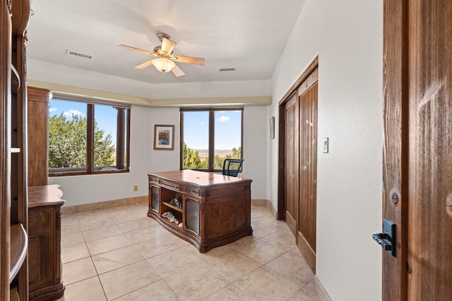 office space with visible vents, a ceiling fan, baseboards, and light tile patterned floors