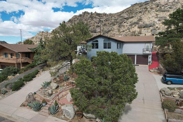 view of front of home with concrete driveway, a balcony, a garage, and stucco siding