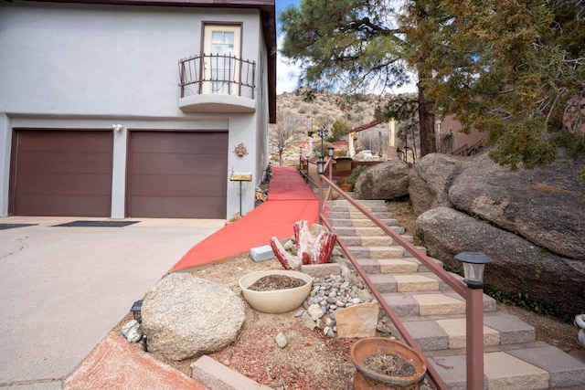 view of property exterior featuring stucco siding, driveway, a balcony, and an attached garage