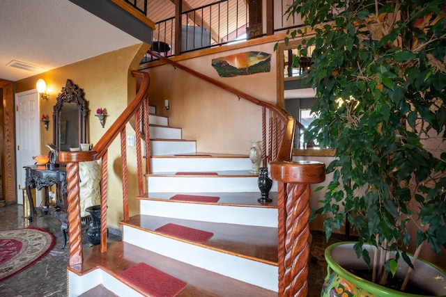 staircase featuring visible vents and a textured ceiling