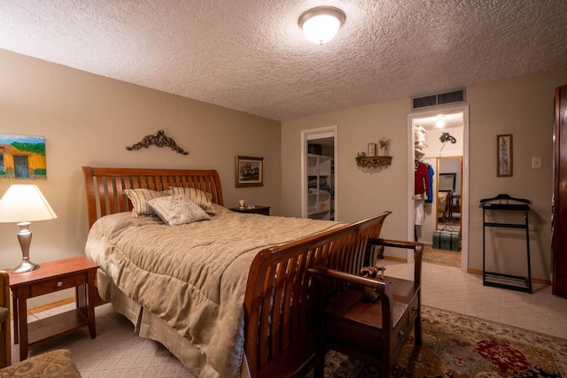 carpeted bedroom featuring visible vents, baseboards, a textured ceiling, and a spacious closet