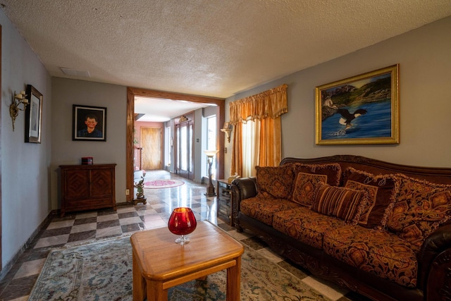 living area featuring tile patterned floors, a textured ceiling, and baseboards