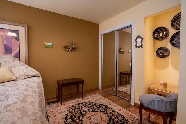 bedroom with visible vents, baseboards, a closet, and wood finished floors