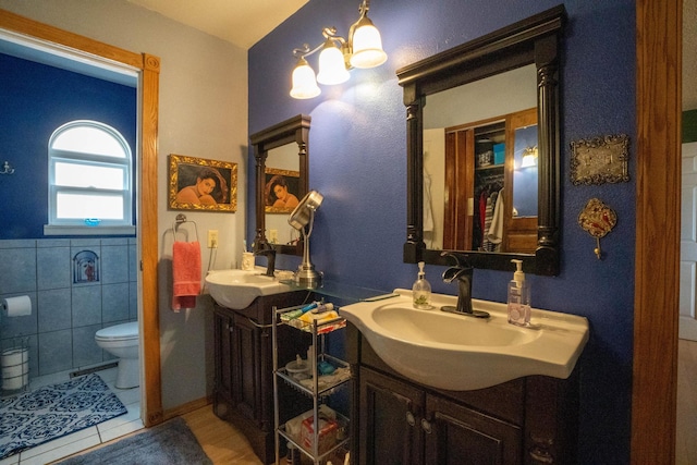 full bathroom with tile walls, tile patterned floors, toilet, and vanity