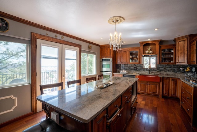 kitchen with decorative backsplash, double oven, dark wood-style flooring, and a sink