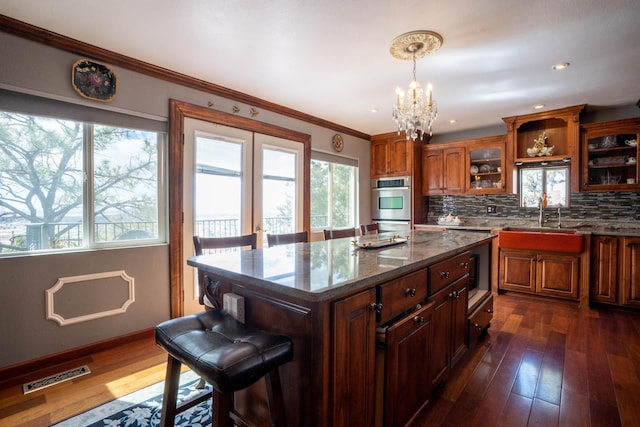 kitchen featuring visible vents, a notable chandelier, a sink, tasteful backsplash, and dark wood-style floors