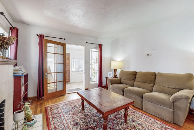 living room featuring wood finished floors, baseboards, a wealth of natural light, and a textured ceiling