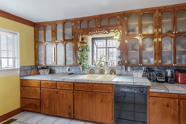 kitchen with a sink, black dishwasher, a healthy amount of sunlight, and light tile patterned floors