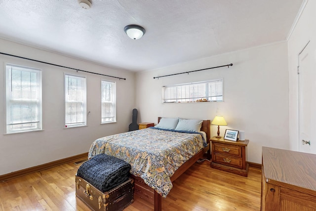 bedroom featuring baseboards, multiple windows, and light wood-style floors