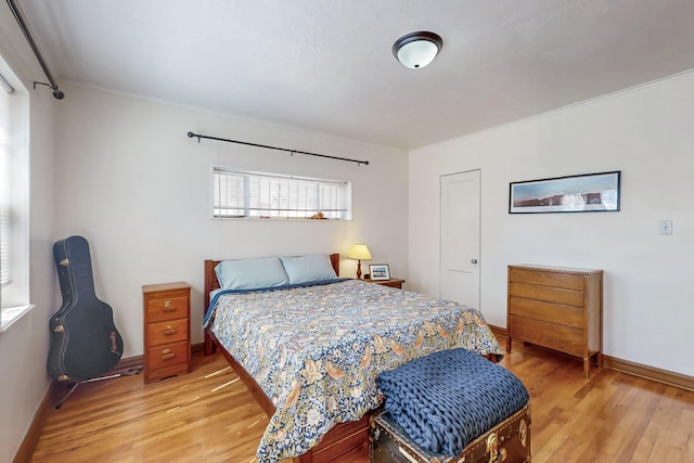 bedroom featuring baseboards, crown molding, and light wood-style floors