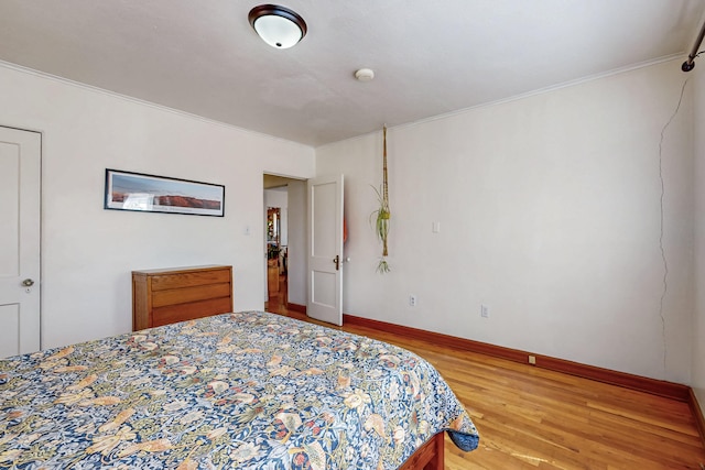 bedroom with light wood-type flooring, baseboards, and ornamental molding