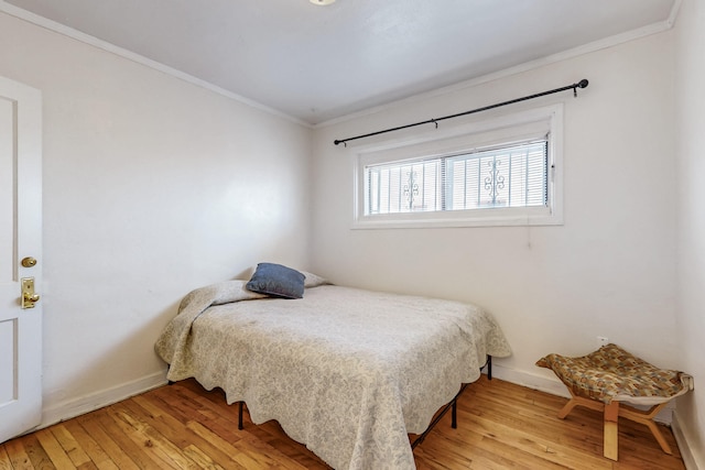 bedroom with baseboards, wood-type flooring, and crown molding