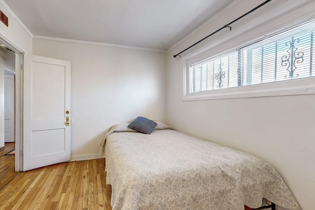 bedroom with baseboards, light wood-style floors, and ornamental molding