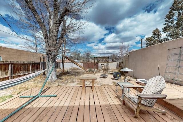 wooden terrace with a fenced backyard and an outdoor fire pit