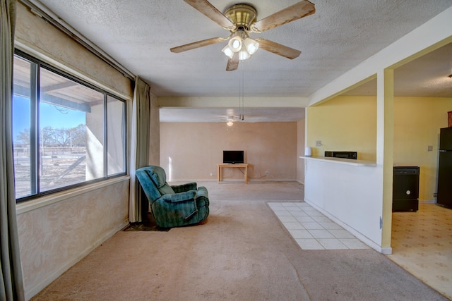 sitting room with a textured ceiling, baseboards, carpet floors, and ceiling fan