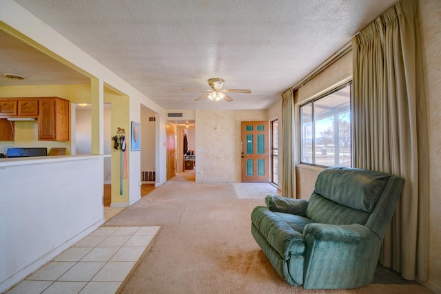 sitting room featuring light carpet, visible vents, a textured ceiling, and a ceiling fan