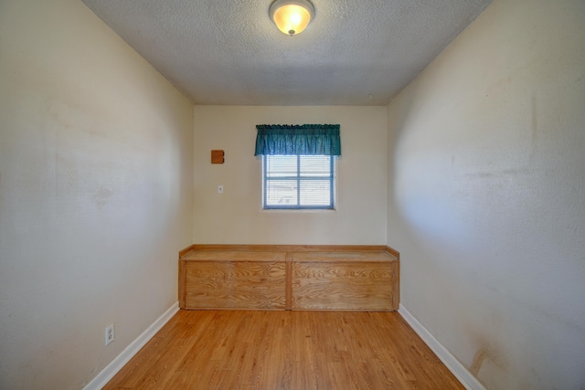 empty room with a textured ceiling, baseboards, and wood finished floors