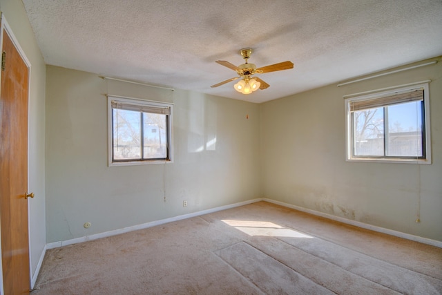 carpeted spare room with a textured ceiling, baseboards, and ceiling fan