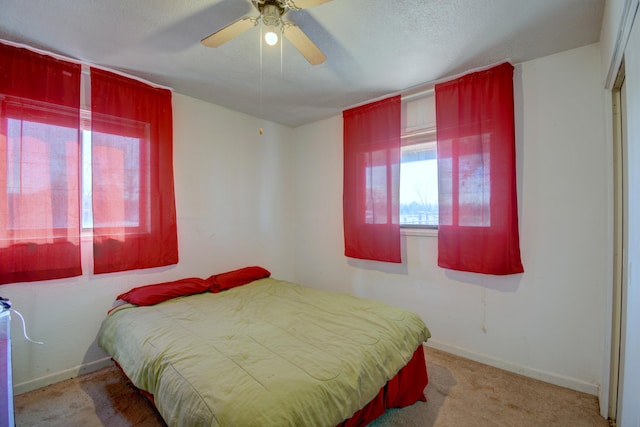 carpeted bedroom with ceiling fan, a textured ceiling, and baseboards