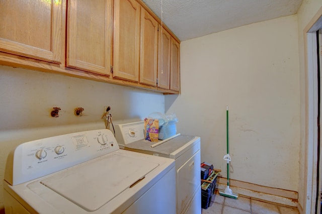 laundry room with a textured ceiling, cabinet space, and washer and clothes dryer