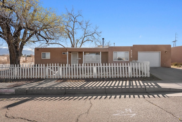 view of front of home featuring driveway, a garage, a fenced front yard, and stucco siding