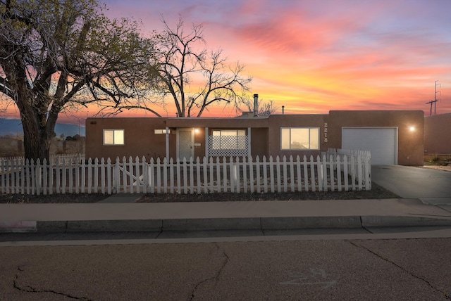 view of front facade with a fenced front yard, stucco siding, concrete driveway, and a garage