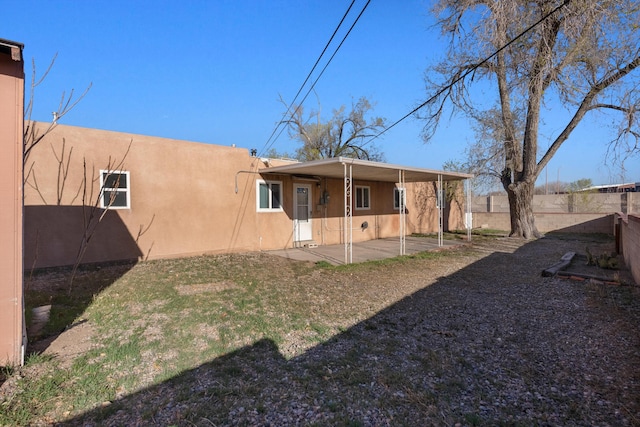 rear view of house featuring a patio, a fenced backyard, and stucco siding