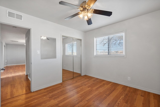 unfurnished bedroom featuring visible vents, baseboards, wood finished floors, a closet, and a ceiling fan