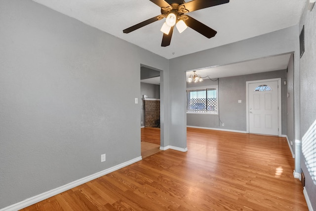 spare room with visible vents, ceiling fan with notable chandelier, light wood-type flooring, and baseboards