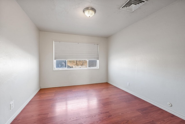 unfurnished room with visible vents, baseboards, and wood finished floors