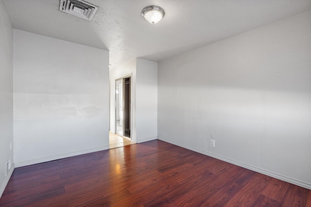 spare room featuring visible vents, baseboards, and wood finished floors