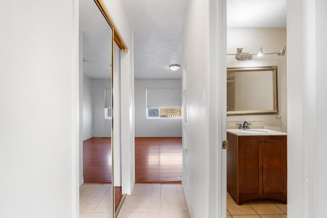 corridor with light tile patterned floors and a sink