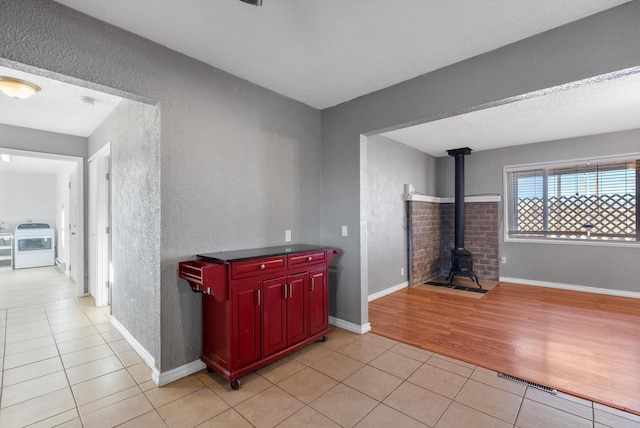 interior space featuring washer / clothes dryer, a textured wall, baseboards, and light tile patterned floors