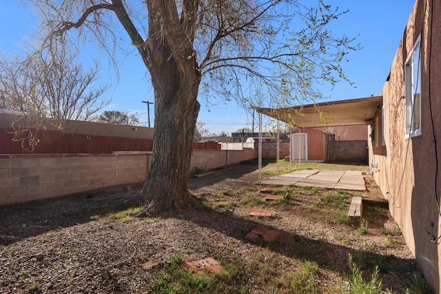 view of yard with a storage unit, an outbuilding, and a fenced backyard