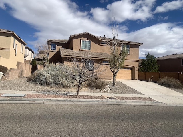view of front facade with stucco siding, a tile roof, fence, concrete driveway, and a garage