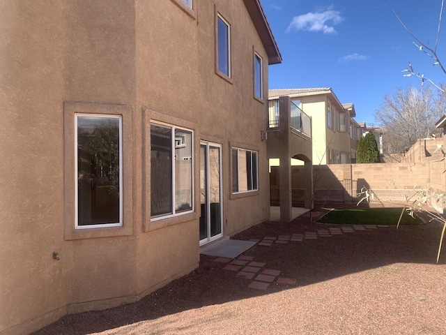 exterior space featuring stucco siding and fence