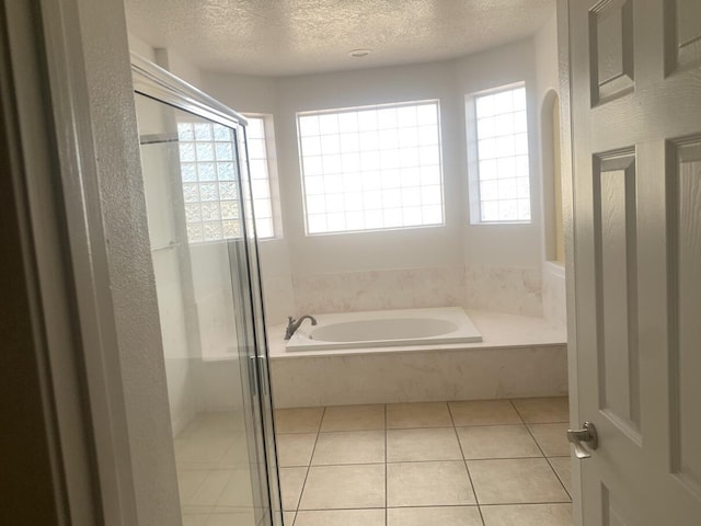 full bathroom with tile patterned floors, a shower stall, a textured ceiling, and a bath