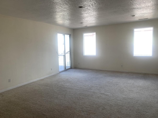 carpeted empty room featuring visible vents, baseboards, and a textured ceiling